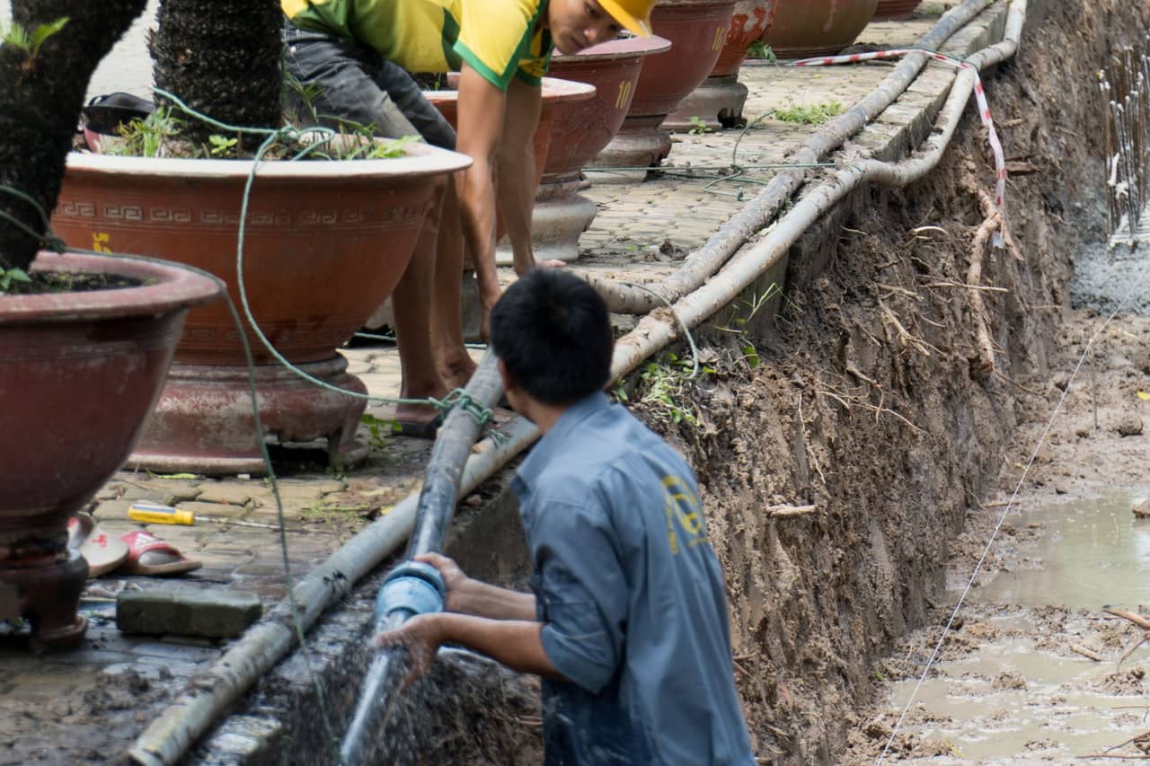 Plumber Naples FL: Two workers repairing a pipe