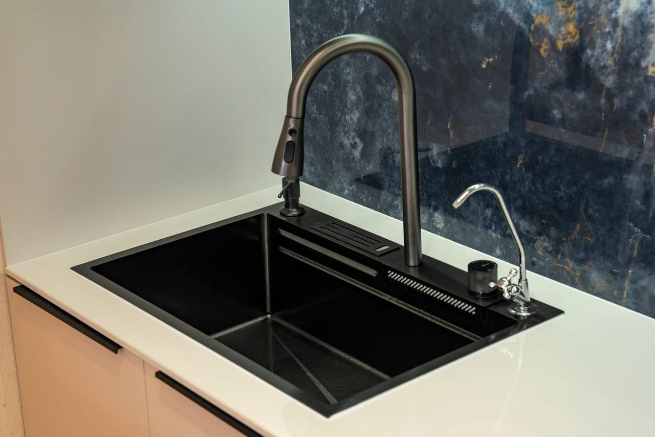 Plumber New Orleans LA: Modern black kitchen sink with marble backsplash
