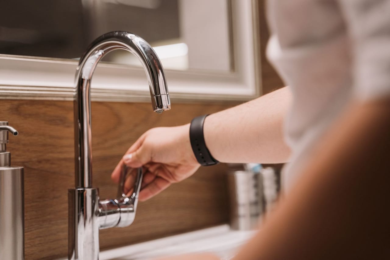 Plumber Oxnard CA: A person turning a faucet handle