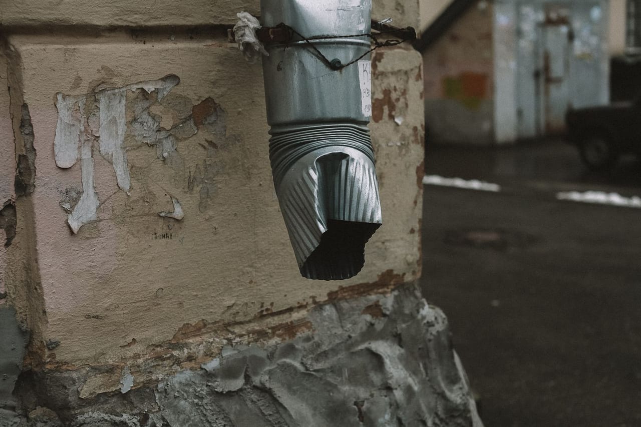 Plumber Pasadena TX: A silver metal pipe on brown concrete wall