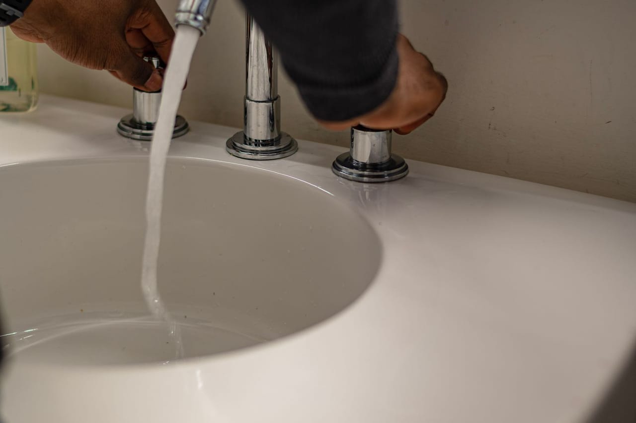 Plumber Raleigh NC: A person's hand holding a silver faucet