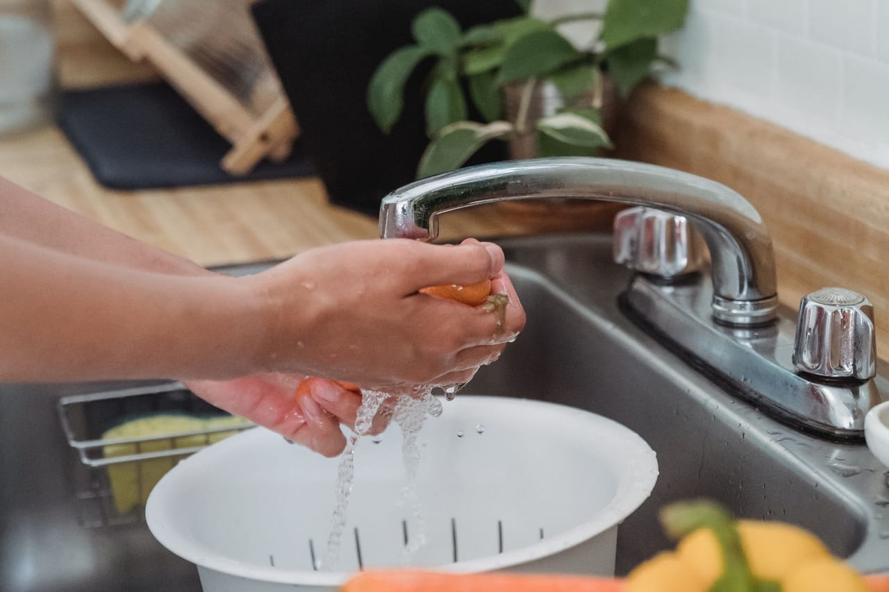 Plumber Tacoma WA: A person washing vegetables on the sink