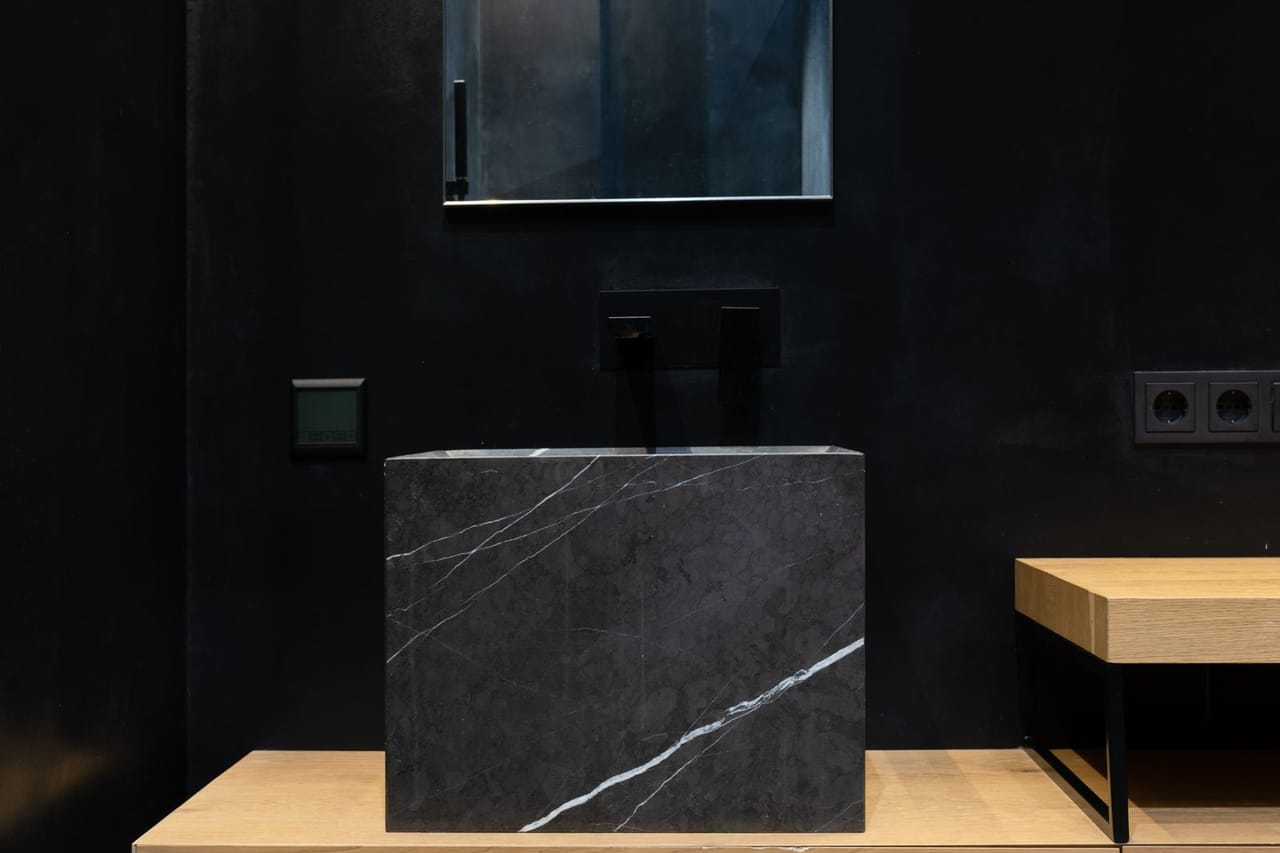 Plumber Victoria TX: Wooden furniture and marble sink in contemporary bathroom with black walls