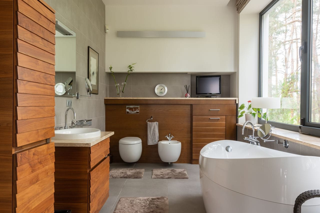 Plumber Warren MI: Bathroom with wooden furniture and clean white bathtub