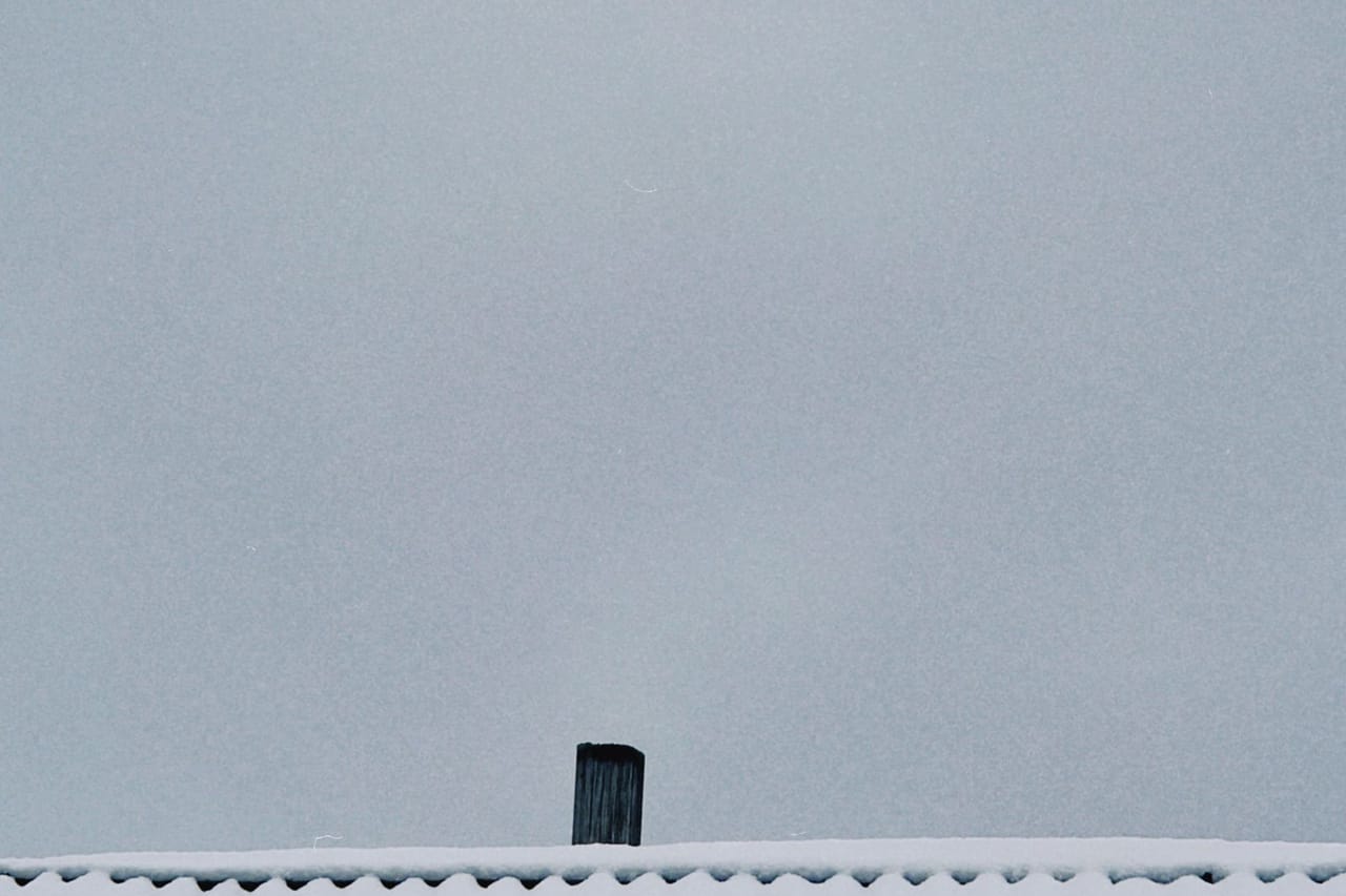 Roof repair Anchorage AK: Snow covered roof with chimney in winter talgar