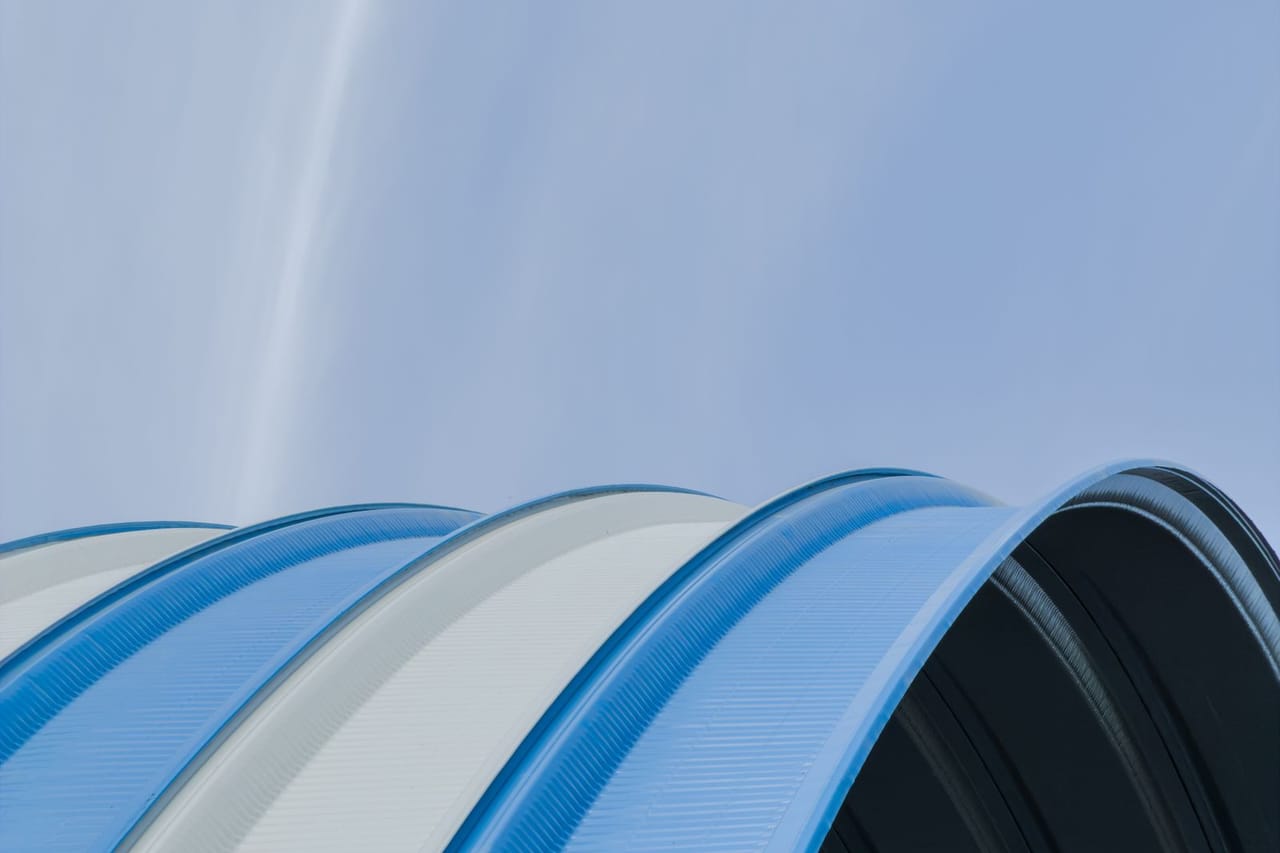 Roof repair Beatrice NE: Modern curved metal roof against blue sky