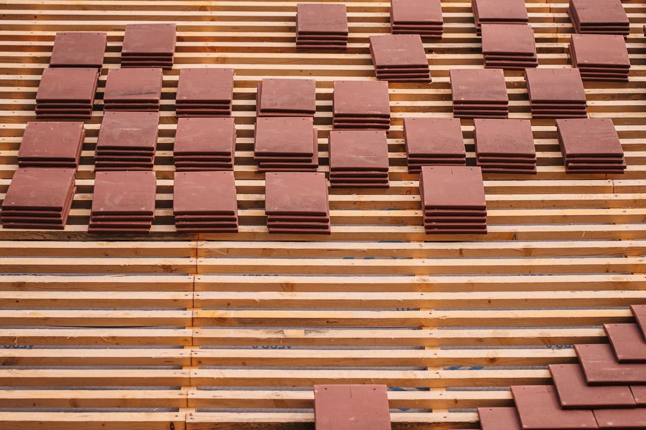 Roof repair Biloxi MS: Partially constructed roof with red tiles and wooden lattice