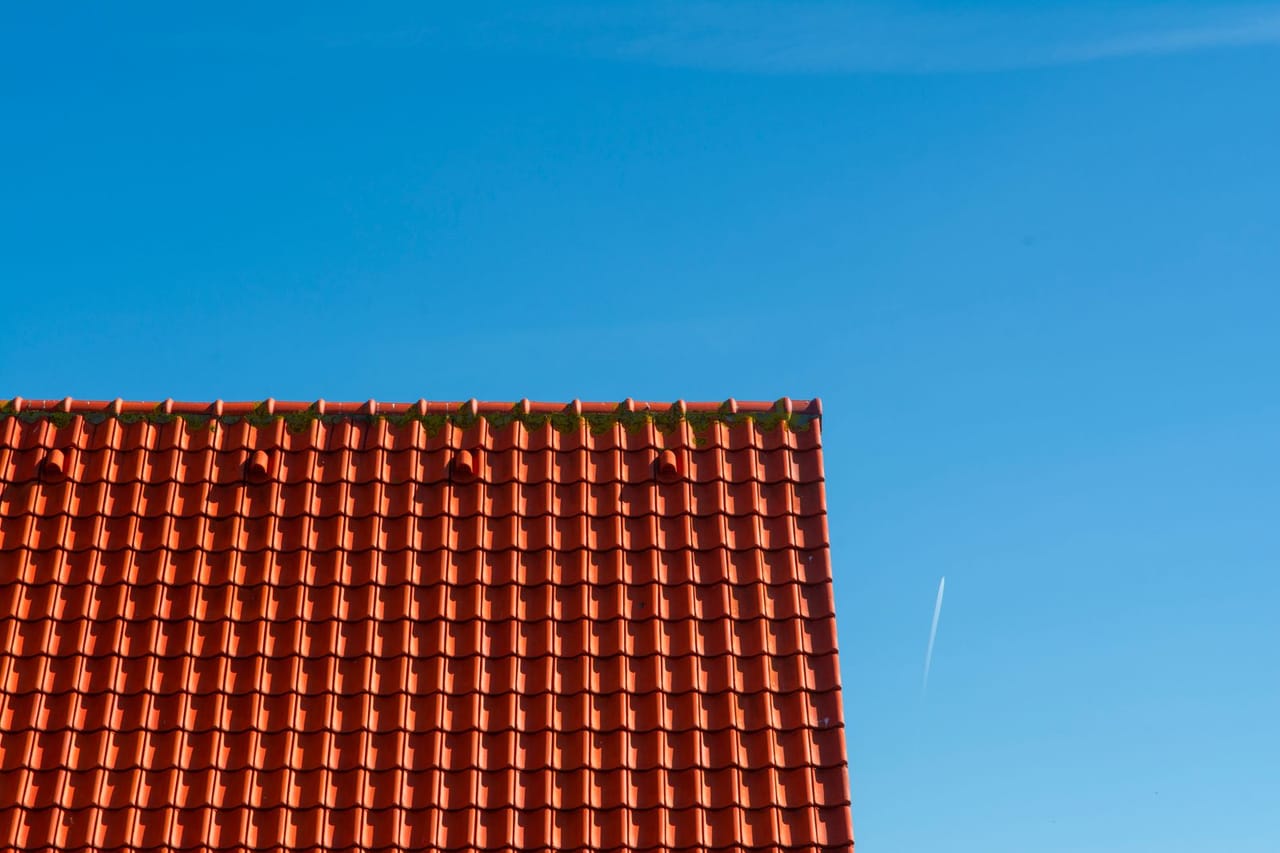 Roof repair Burlington NC: Roof with red tiles on the background of clear blue sky