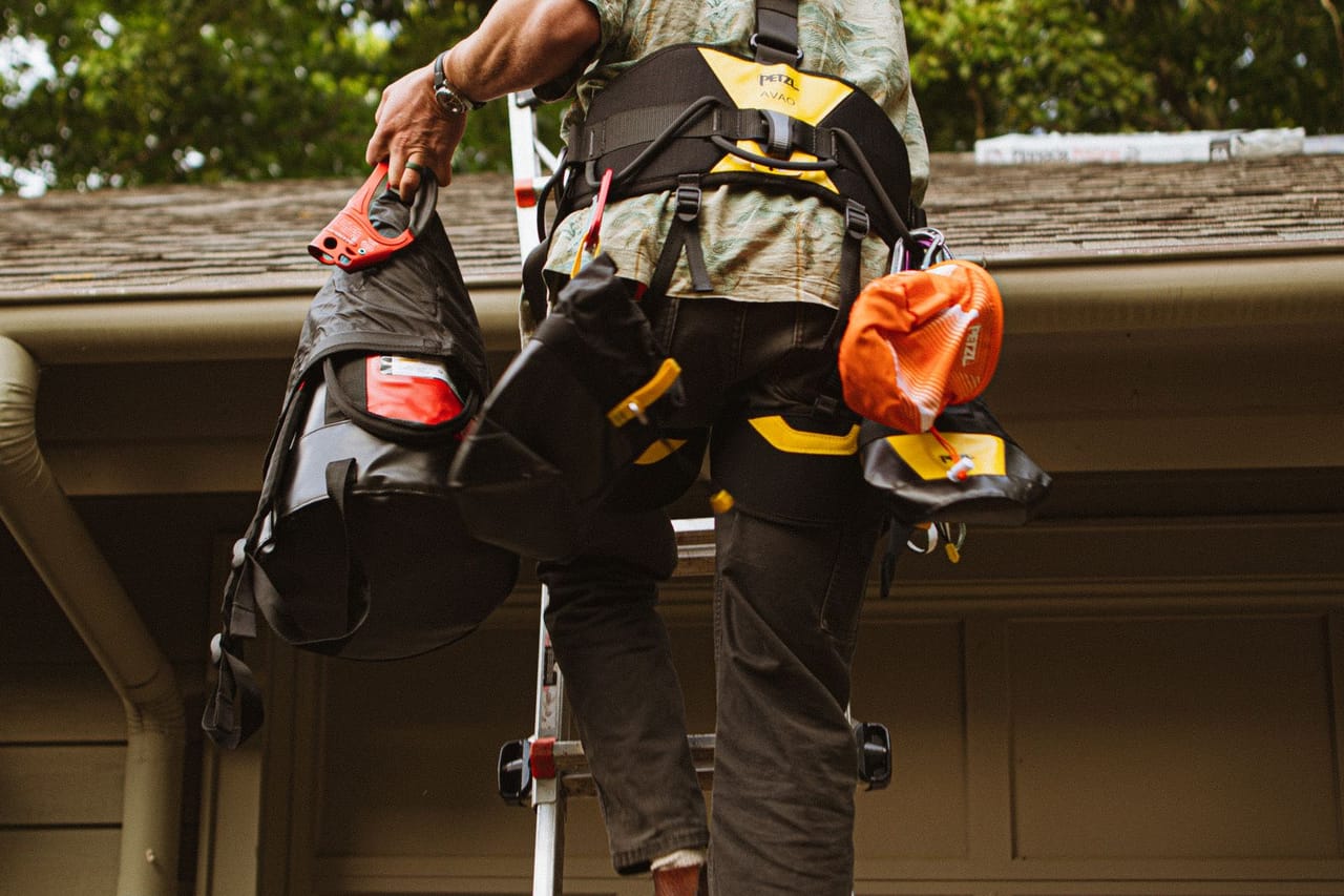 Roof repair Conway AR: Skilled roofer climbing ladder for repair