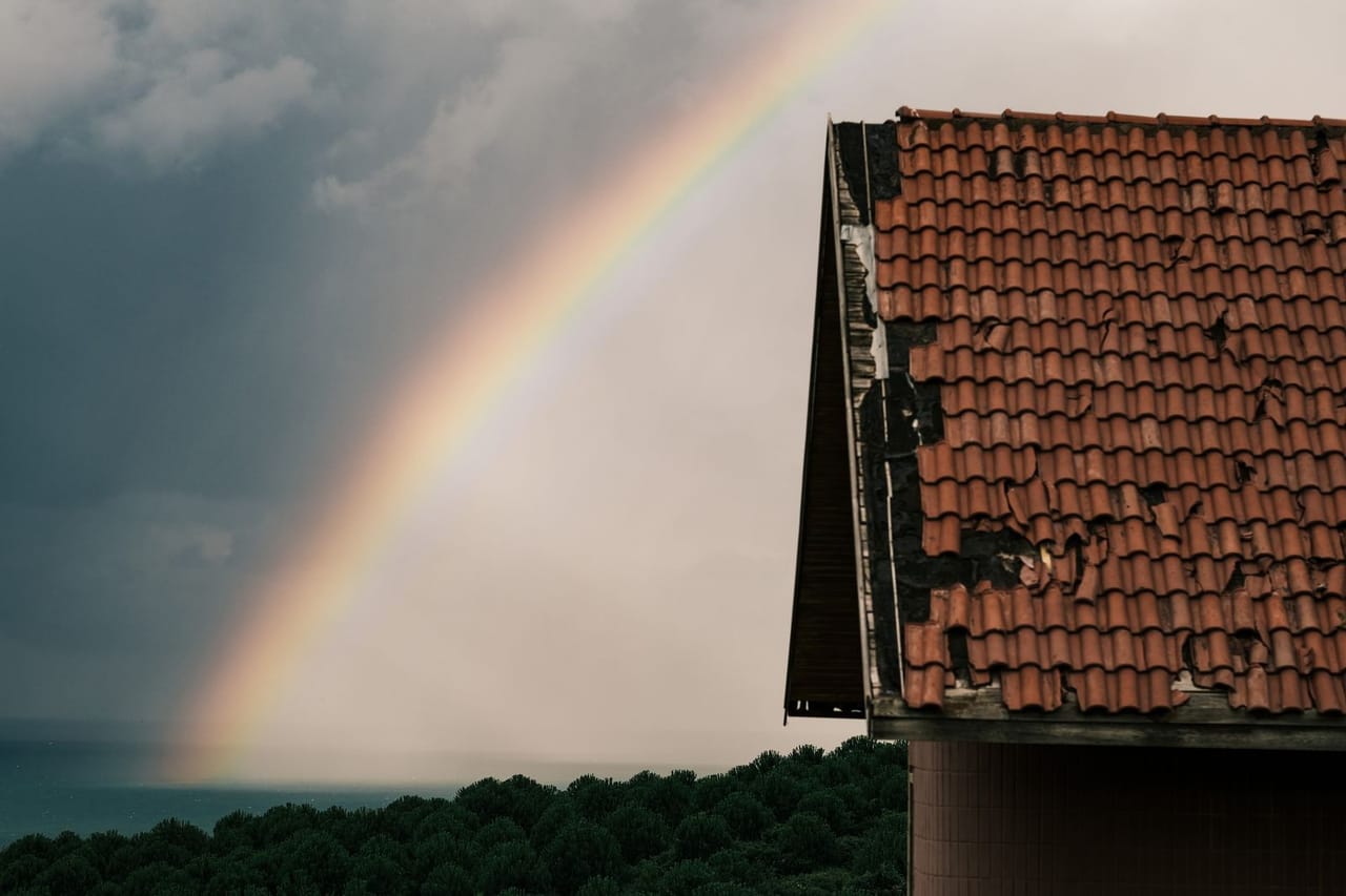 Roof repair Corpus Christi TX: Rainbow over sea behind roof