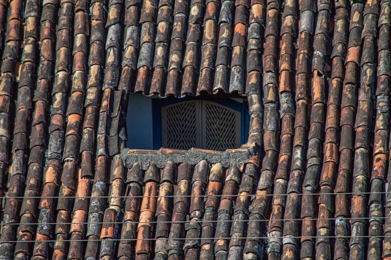 Roof repair Iowa City IA: Rustic clay tile roof with window opening