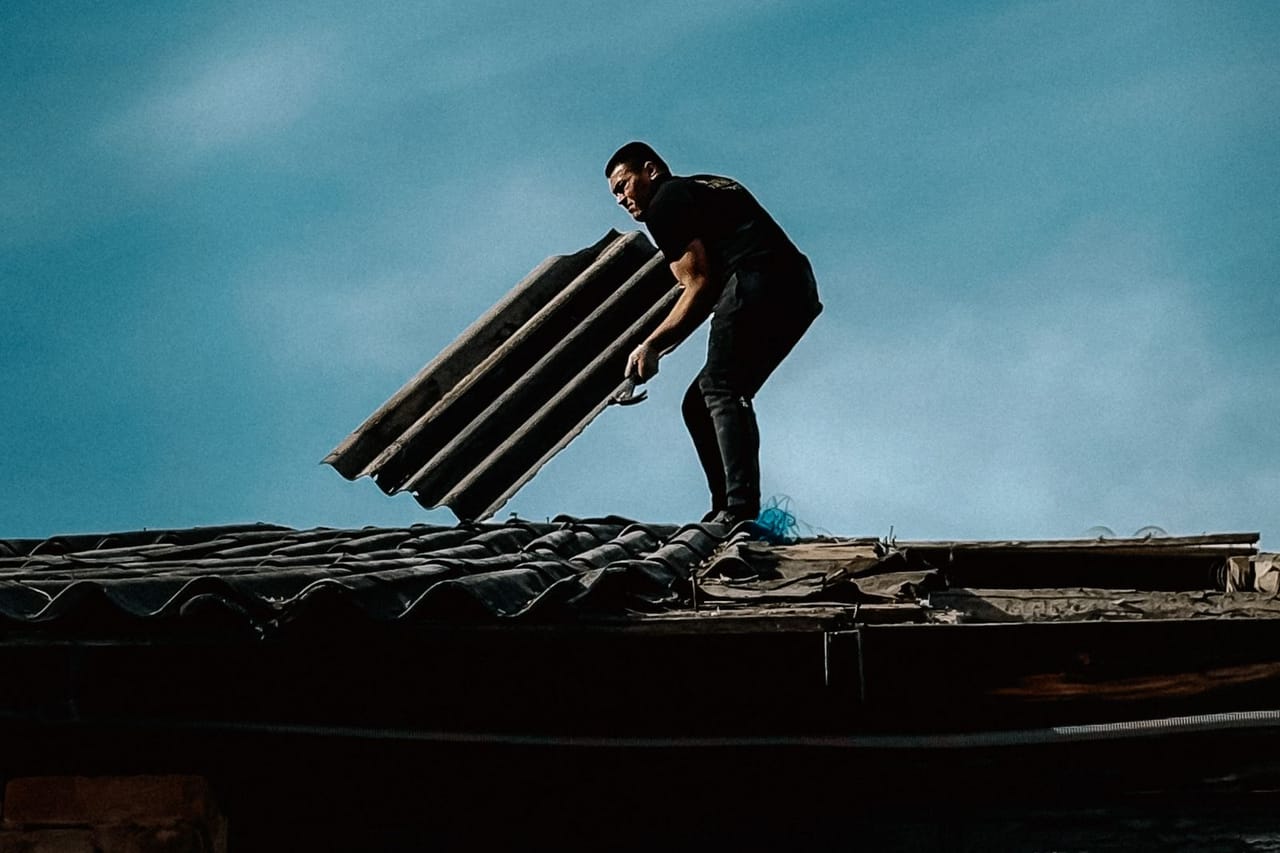 Roof repair Mesa AZ: Man working on rooftop under blue sky