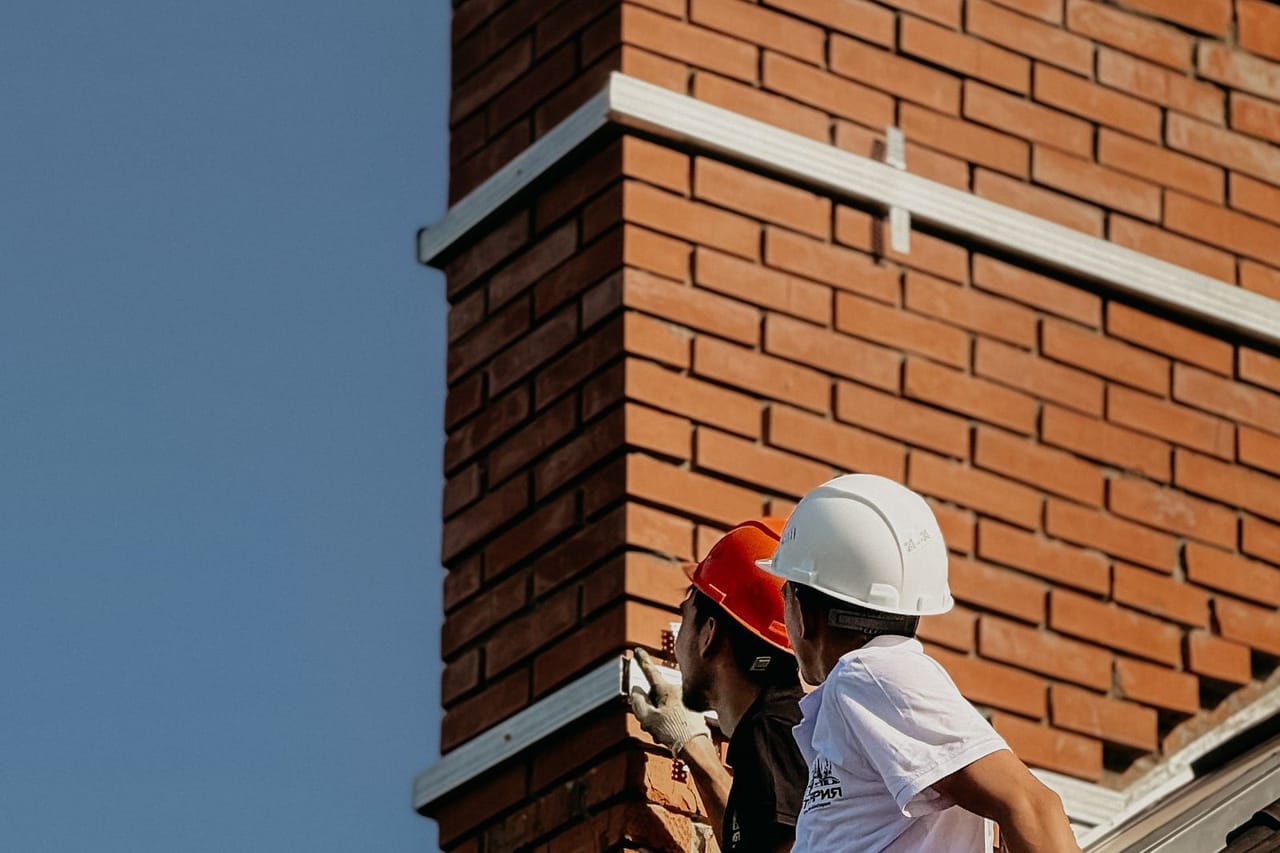 Roof repair in Miami: Construction workers repairing chimney on rooftop