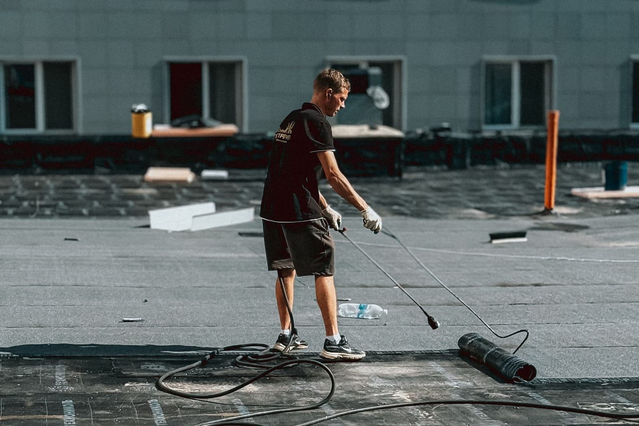 Roof repair Oxnard CA: Construction worker applying roofing material