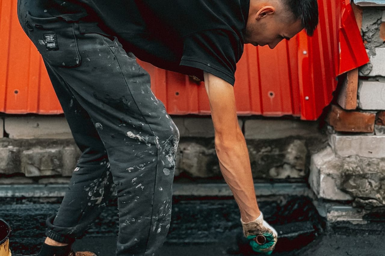 Roof repair Palm Bay FL: Young man working on rooftop waterproofing