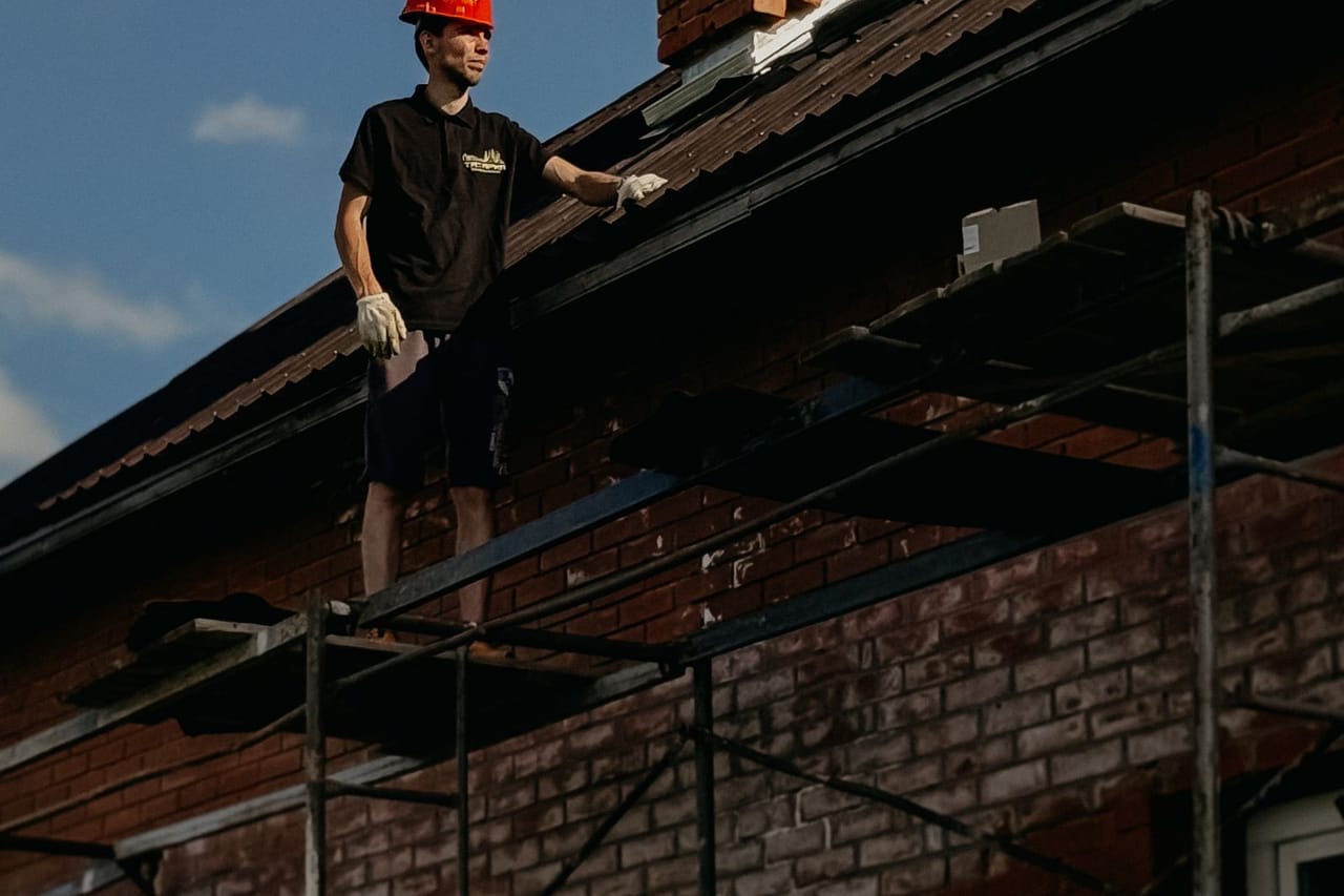 Roof repair Palo Alto CA: Construction worker on scaffold by brick chimney