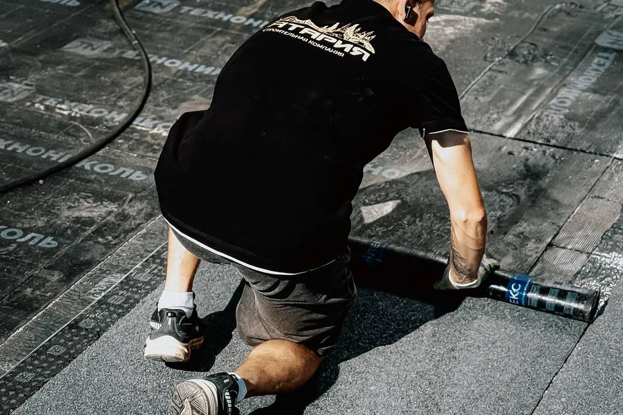 Roof repair Pampa TX: Worker applying roofing material on construction site