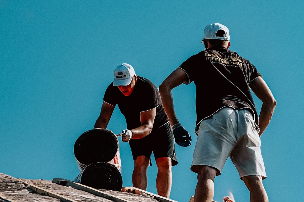 Roof repair Peoria AZ: Construction workers roofing under clear blue sky