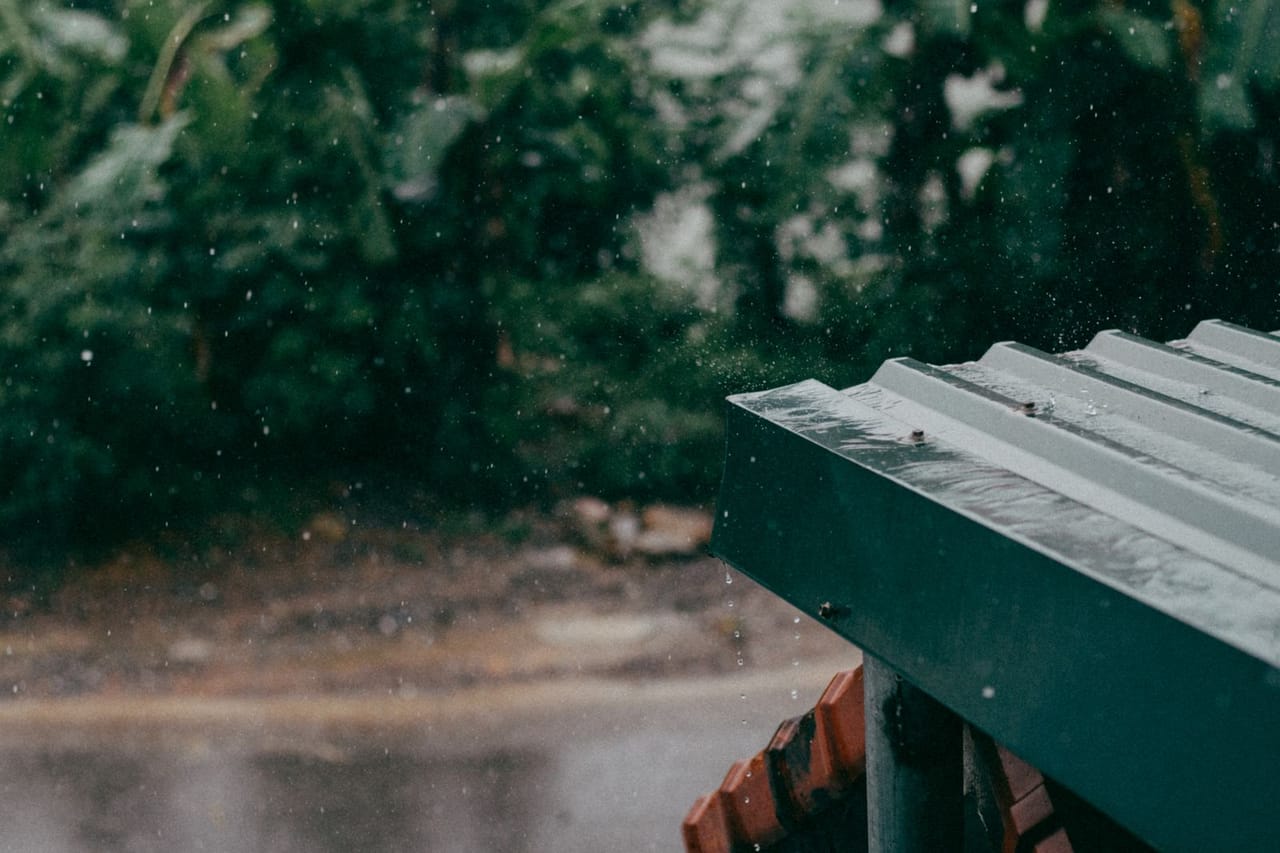 Roof repair Pontiac MI: Metal sheet rooftop on rainy day