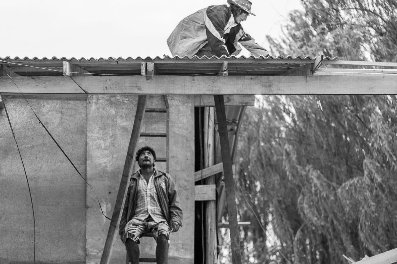 Roof repair Sacramento CA: A man sitting on a ladder leaning on a concrete wall