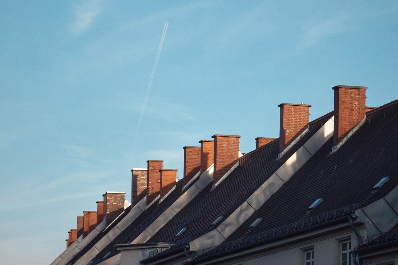 Roof repair Santa Barbara CA: Row of classic rooftop chimneys against blue sky