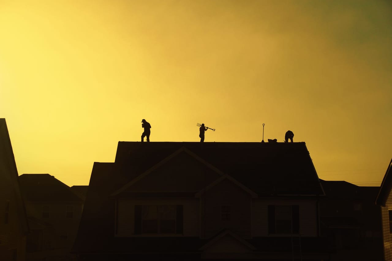 Roof repair Slidell LA: Silhouette of roofers working at sunset
