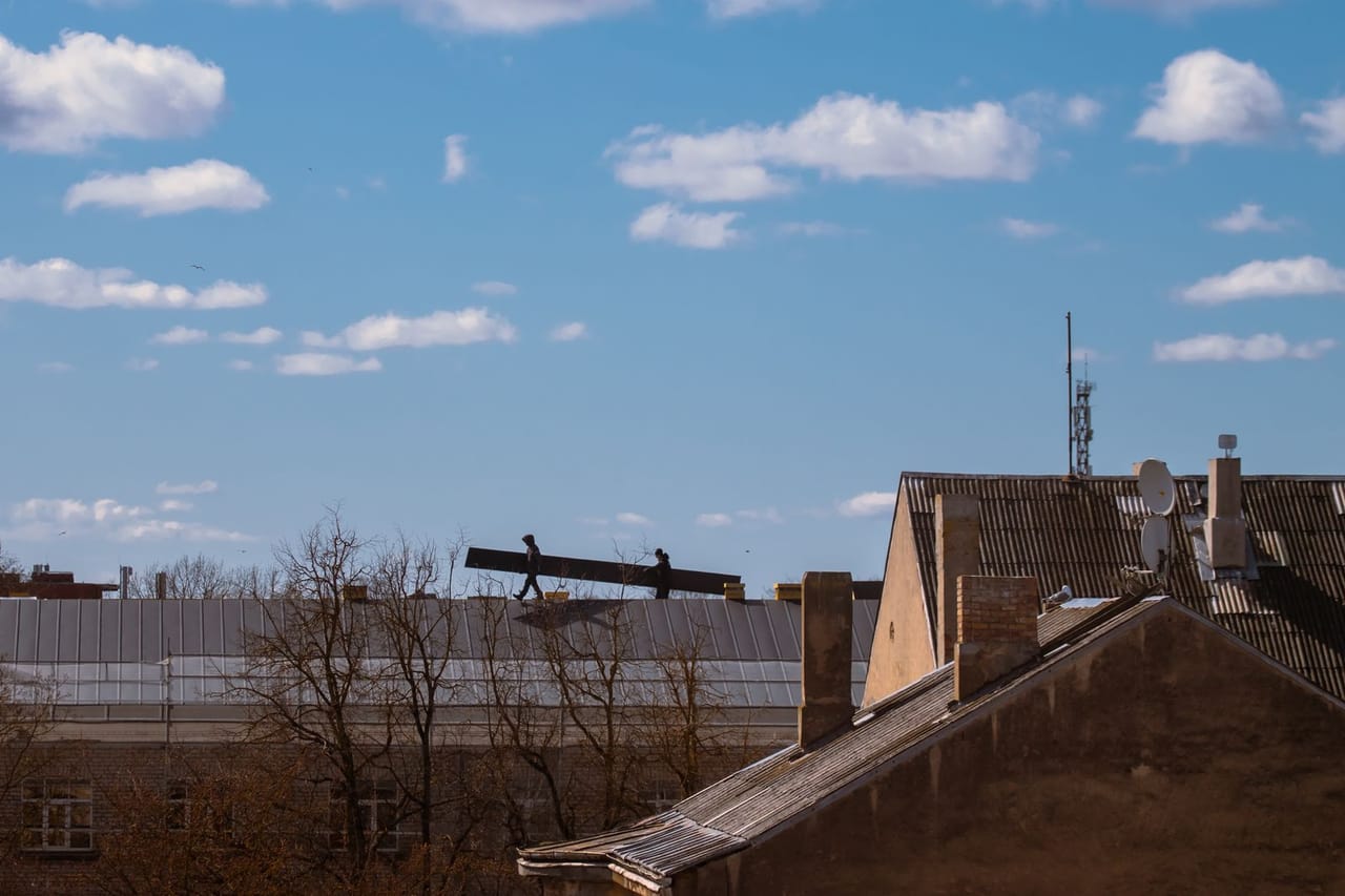 Roof repair St Joseph MO: Silhouetted workers on rooftop against blue sky