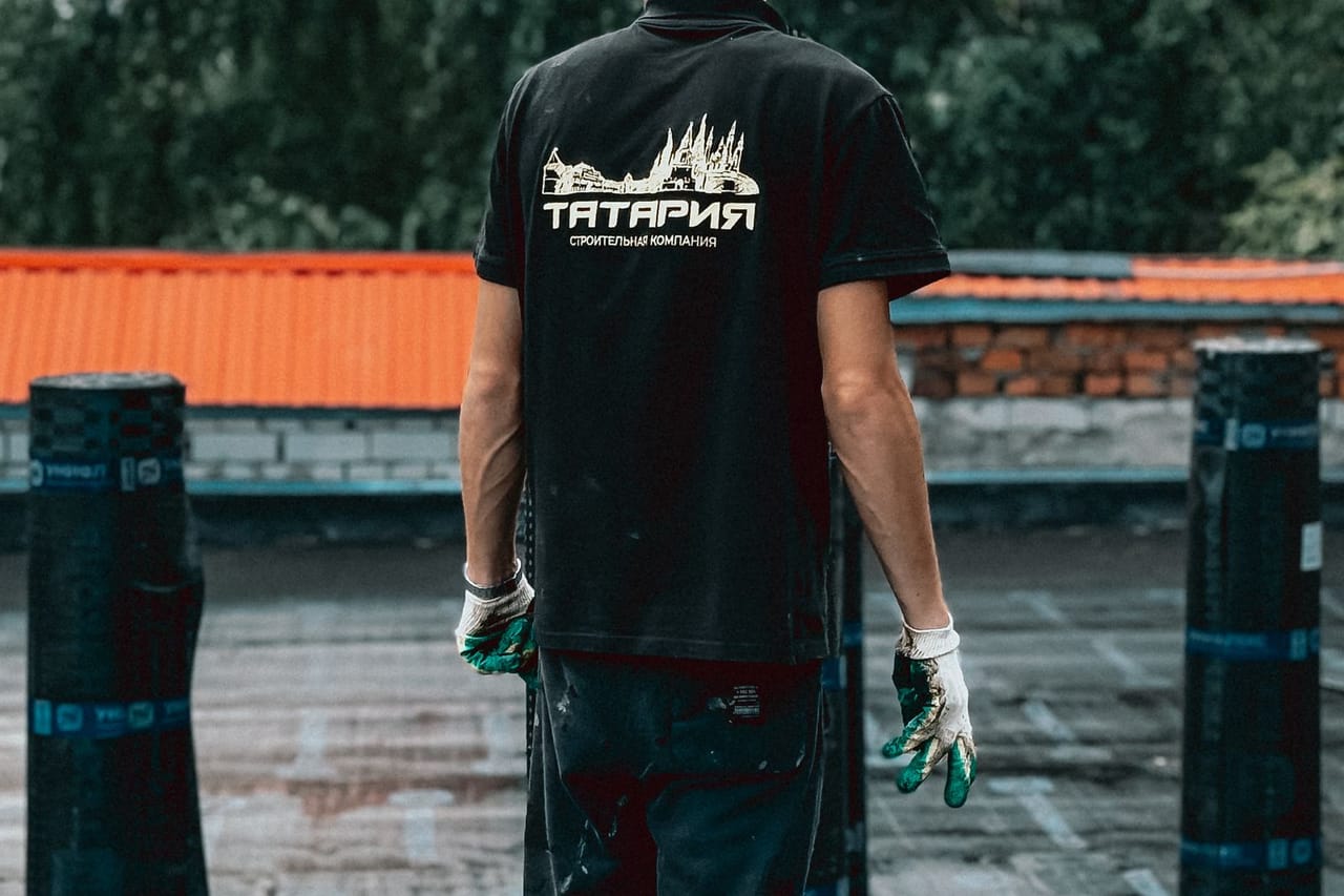 Roof repair St Louis MO: Roofer on a building top with scenic trees
