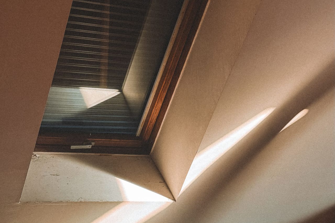 Roof repair Toledo OH: Sunlit attic window with wooden interior