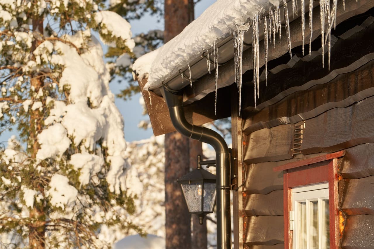 Roof repair Wilmington NC: Close up of icicles on old wooden house in winter