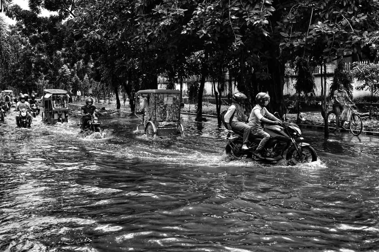 Water damage restoration Modesto CA: People riding motorbikes and rickshaws on street during flood