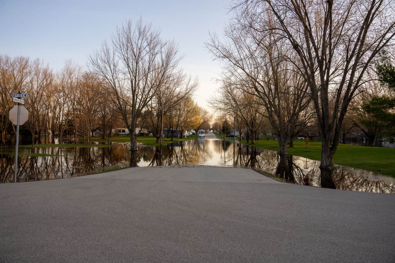 Water damage restoration Overland Park KS: A flooded road with trees and a park in the background