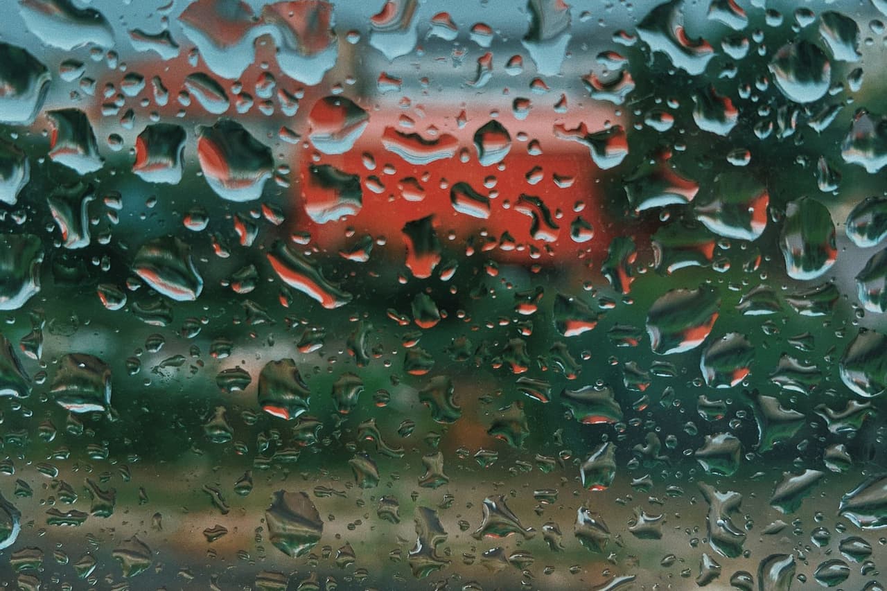 Water damage restoration Richmond VA: Raindrops on glass window with street in background