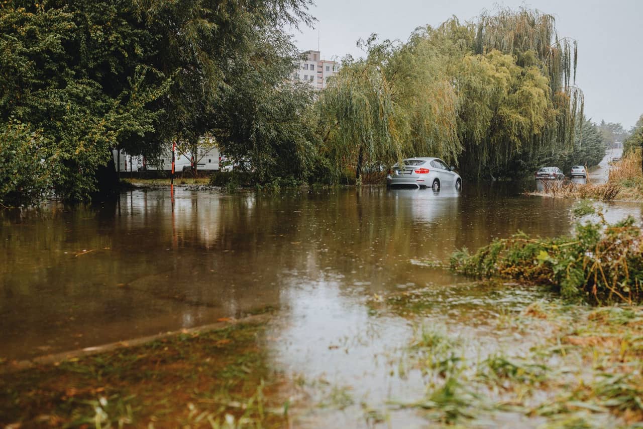 Water damage restoration San Francisco CA: Car navigating flooded road in urban area