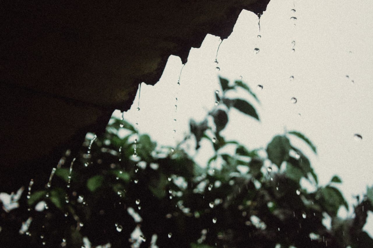 Water damage restoration San Luis Obispo CA: Raindrops falling from roof at dusk
