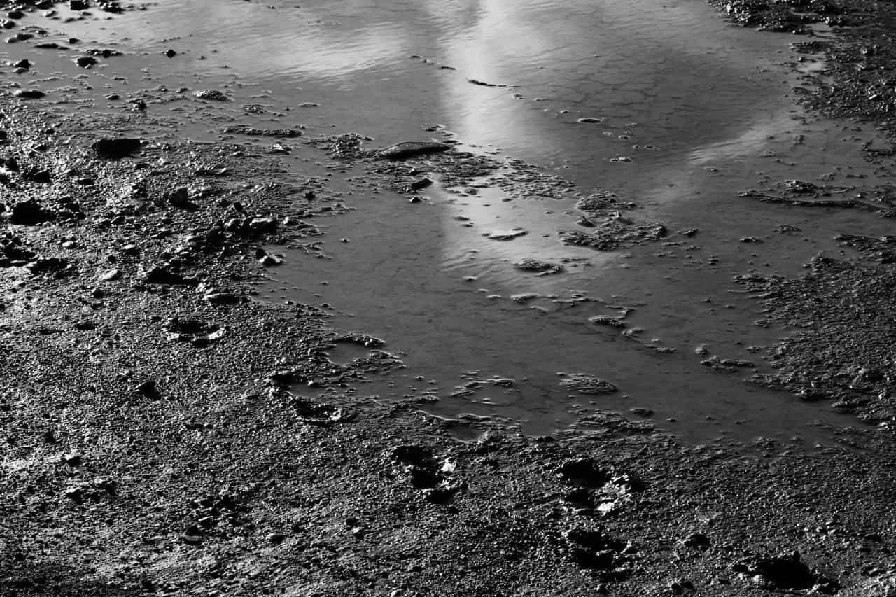 Water damage restoration Sulphur Springs TX: Black and white puddle reflection on dirt road