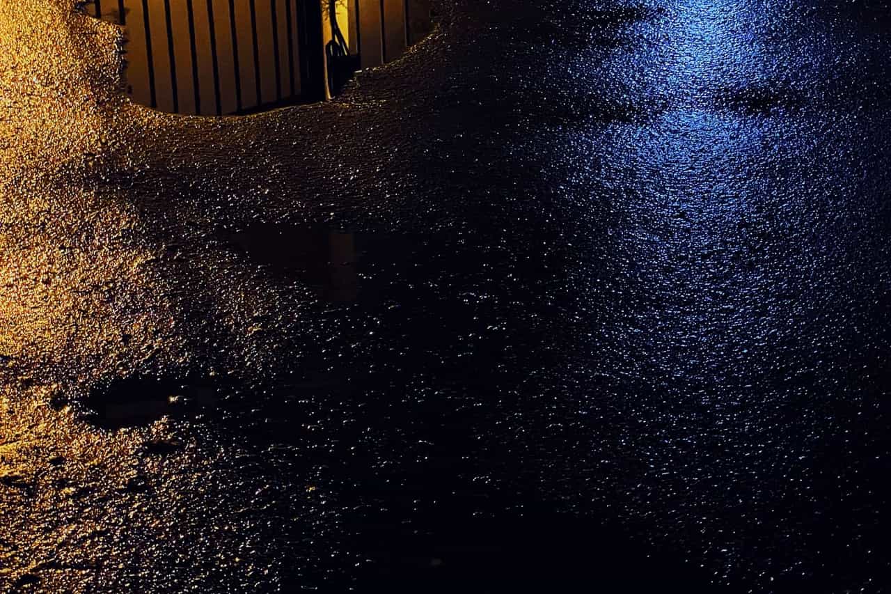 Water damage restoration Warwick RI: Black asphalt road with puddle during night time