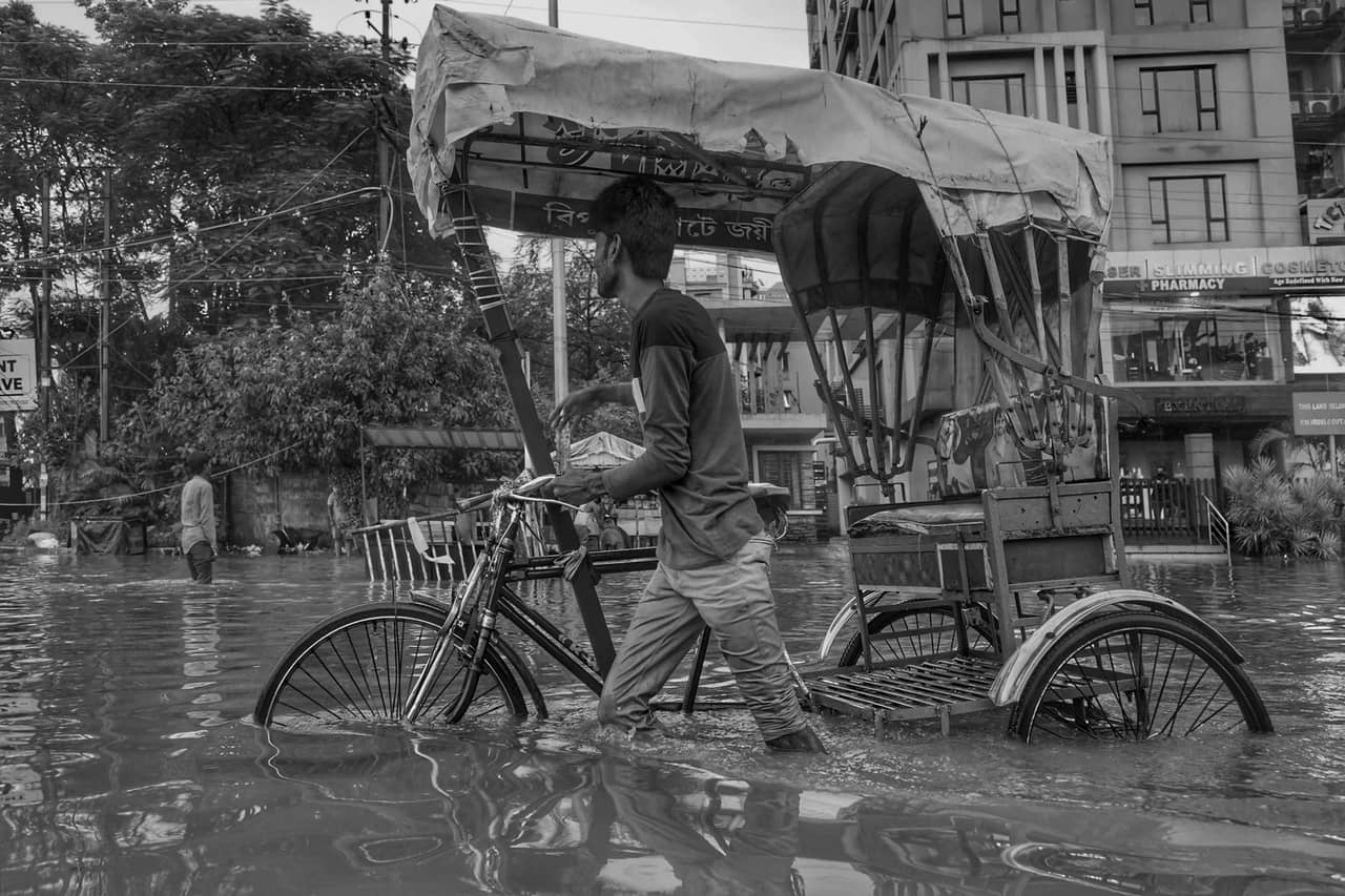 Water damage restoration Youngstown OH: A man pushing a rickshaw on a flooded street